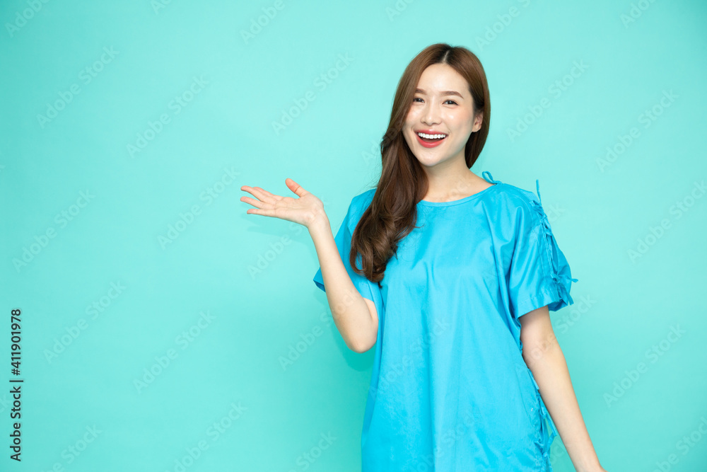 Wall mural young asian woman wearing patient outfits presenting or showing open hand palm with copy space for p