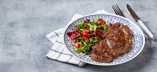 Grilled steaks and vegetable salad on light background. Table setting, food concept