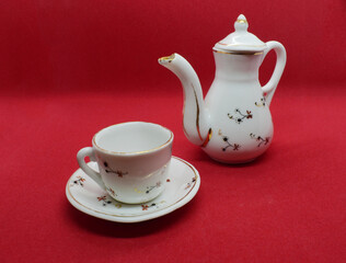 Teapot and cup with saucer on a red background