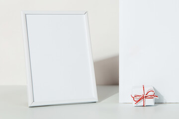 Kraft gift with a red ribbon and photo frame on a white background, the concept of the Valentines day, congratulations. Copy space.