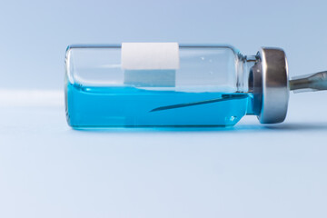 A vial with a blue vaccine with a syringe needle inside
