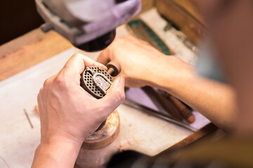 A male jeweler fixes precious stones on a silver pendant