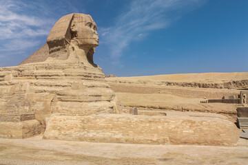Fototapeta na wymiar The great Sphinx of Giza in the desert near Cairo. It's a close-up without people. A sunny day with some clouds in the blue sky.