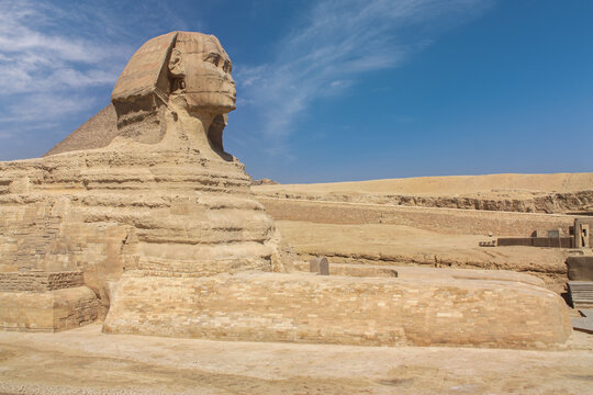 The great Sphinx of Giza in the desert near Cairo. It's a close-up without people. A sunny day with some clouds in the blue sky.
