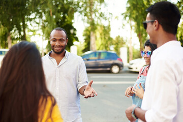 Young people having fun outdoors. A group of multi-ethnic friends are talking and laughing while standing in the street