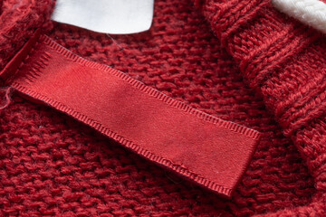 Blank laundry care clothes label on red knitted fabric texture background