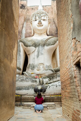 Asian woman to pay respect to Buddha statue at Wat Si Chum ,an ancient religious site of sukhothai...