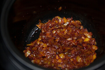 Chopped onion is fried with tomato paste in a multicooker pan.