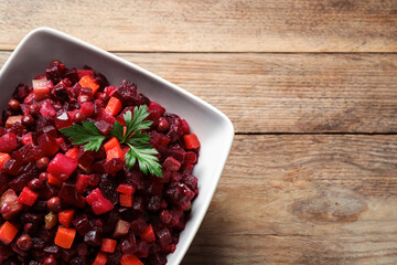 Traditional Russian vinaigrette salad on wooden table, top view. Space for text