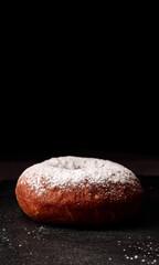 donut sprinkled with powdered sugar on a black background