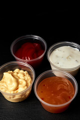 ketchup creamy cheese and sweet and sour sauces on black background