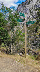 Cain, Spain - September 1, 2020: Wooden signpost with directional signs on hiking trail in the Cares Route in the heart of Picos de Europa National Park, Cain-Poncebos, Asturias, Spain.