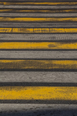 Pedestrian crossing with semi-erased white and yellow stripes.