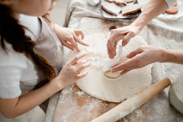 Fototapeta premium Photo of dough with cut out figures lying on the table in flour with hands