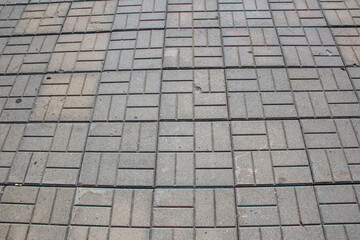 The sidewalk is paved with square decorative tiles.