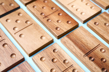 Wooden domino tiles on light blue background, closeup
