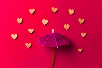 Pink umbrella with heart raindrops on a red background. Copy space. Congratulations to Valentine's day and wedding..