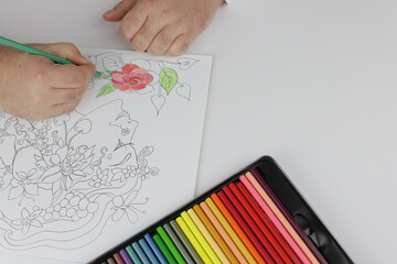 Drawing red rose in mandala antistress with multicoloured pencils during lockdown in quarantine.