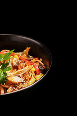 wok noodles with vegetables greens and sesame seeds in a plate on a black background