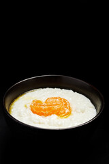 milk rice porridge with orange in a plate on a black background