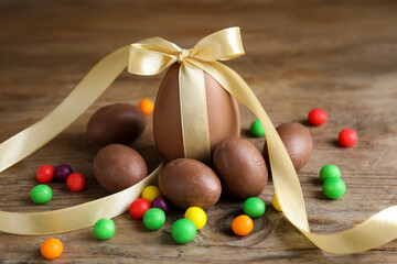 Tasty chocolate eggs and colorful candies on wooden table