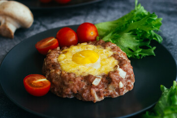 Beefsteak with egg on a plate. Delicious hot dish. The dish is decorated with cherry tomatoes and herbs. Beefsteak on a plate 