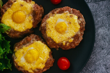 Beefsteak with egg on a plate. Delicious hot dish. The dish is decorated with cherry tomatoes and herbs. Beefsteak on a plate 