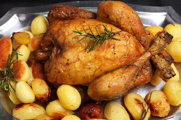 Pollo allo spiedo con contorno di patate novelle su un vassoio di acciaio.
