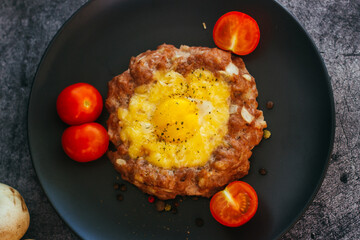 Beefsteak with egg on a plate. Delicious hot dish. The dish is decorated with cherry tomatoes and herbs. Beefsteak on a plate 