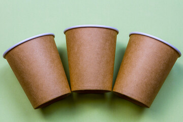 Three paper cups made of eco kraft paper on the green background. Zero waste concept