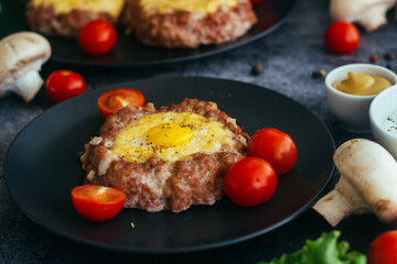 Beefsteak with egg on a plate. Delicious hot dish. The dish is decorated with cherry tomatoes and herbs. Beefsteak on a plate 