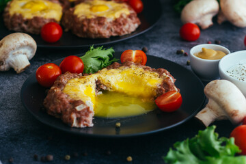 Beefsteak with egg on a plate. Delicious hot dish. The dish is decorated with cherry tomatoes and herbs. Beefsteak on a plate 