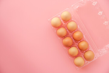 Plastic tray with  eggs on a pink pastel background,  top view