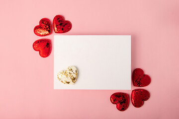 Isolated blank greeting card on the pink backround.Red and white hearts near it. Mockup with copy space.Good for 14 february,greeting for Valentines day.