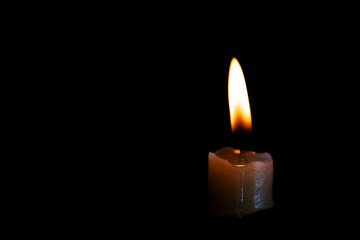 Light candle burning brightly in the black background