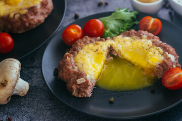 Beefsteak with egg on a plate. Delicious hot dish. The dish is decorated with cherry tomatoes and herbs. Beefsteak on a plate 