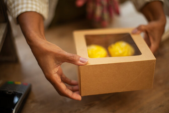 Close up female baker holding boxed cupcakes