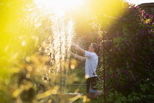 Man adjusting sprinkler in sunny summer garden