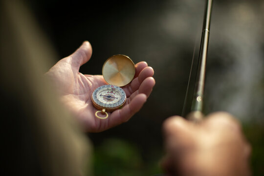 Close up man holding fishing pole and compass