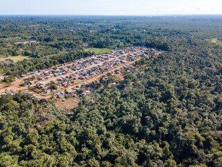 Aerial view of built village houses and forest trees in deforestation area in the Amazon...
