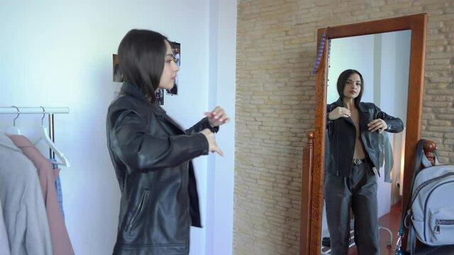 Beautiful woman is Looking for what to wear. Thinking how to put together an outfit. Trying on Leather Jacket