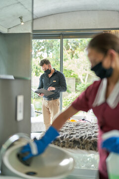 Maids in face masks cleaning and inspecting hotel room