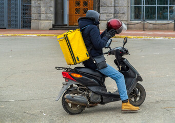 Delivery boy of takeaway on scooter with isothermal food case box. Express food delivery service from cafes and restaurants. Courier on the moto scooter delivering food