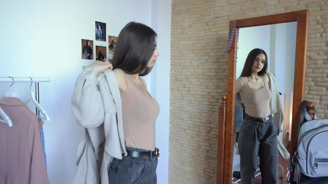 Attractive stylish woman is Looking for what to wear. Looking in the mirror. Tutting on New Shirt