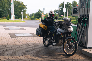 The adventure motorcycle with bags is at a gas station. Fuel quality, price and distance concept....