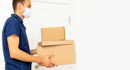 Delivery man holding cardboard boxes in medical mask. copy space. Fast and free Delivery transport . Online shopping and Express delivery . Quarantine