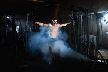 athlete doing pectoral muscle exercise atmospheric smoke in the gym