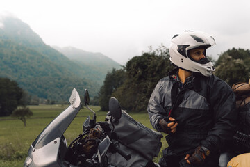 A motorcycle driver with motorbike, Adventure vacation, biker dressed in raincoat. sealed bag,...