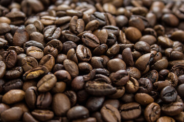 Roasted coffee beans scattered on a wooden table.