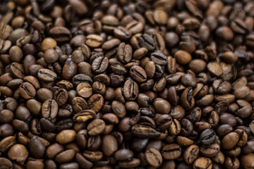 Roasted coffee beans scattered on a wooden table.